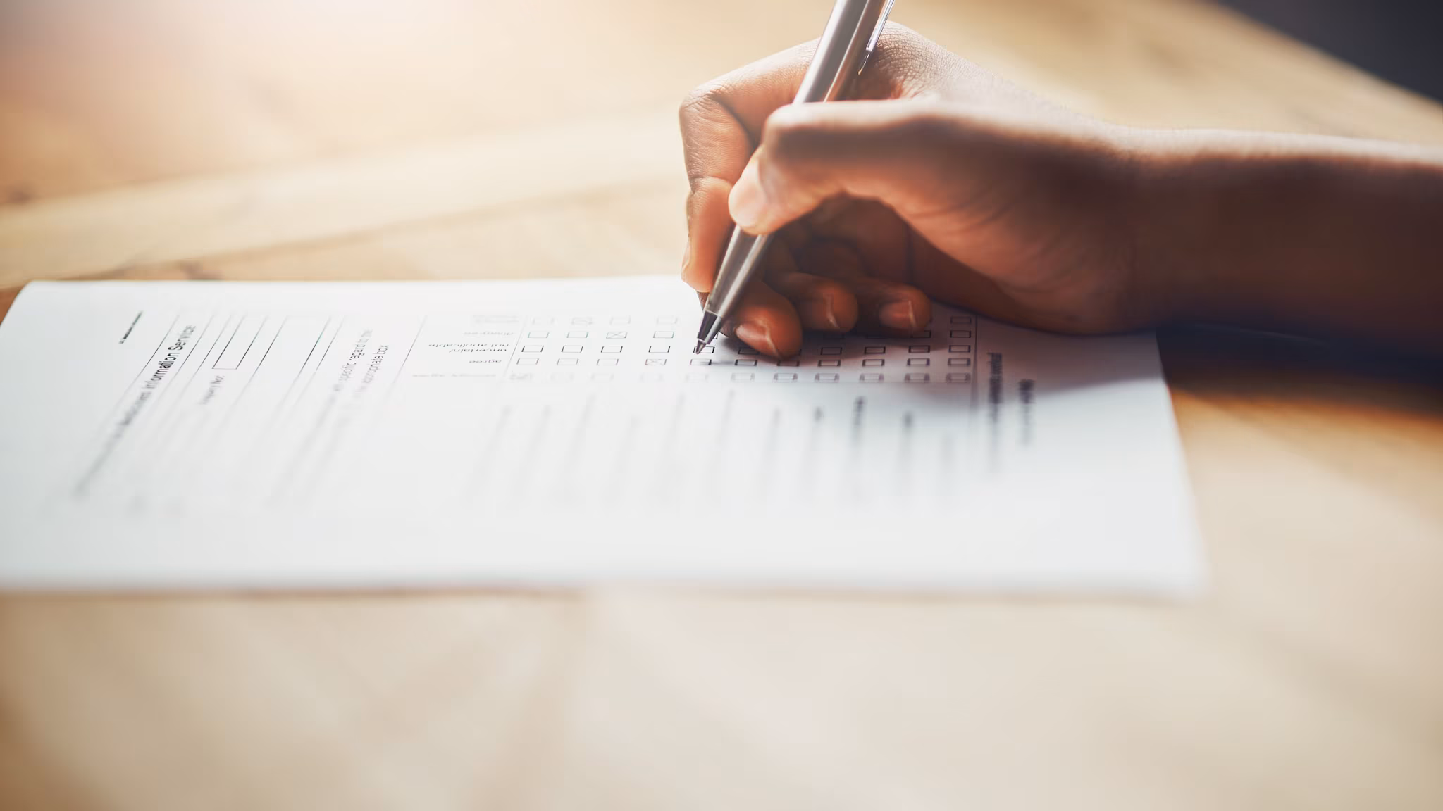 — title missing — Hand with pen filling out a form.