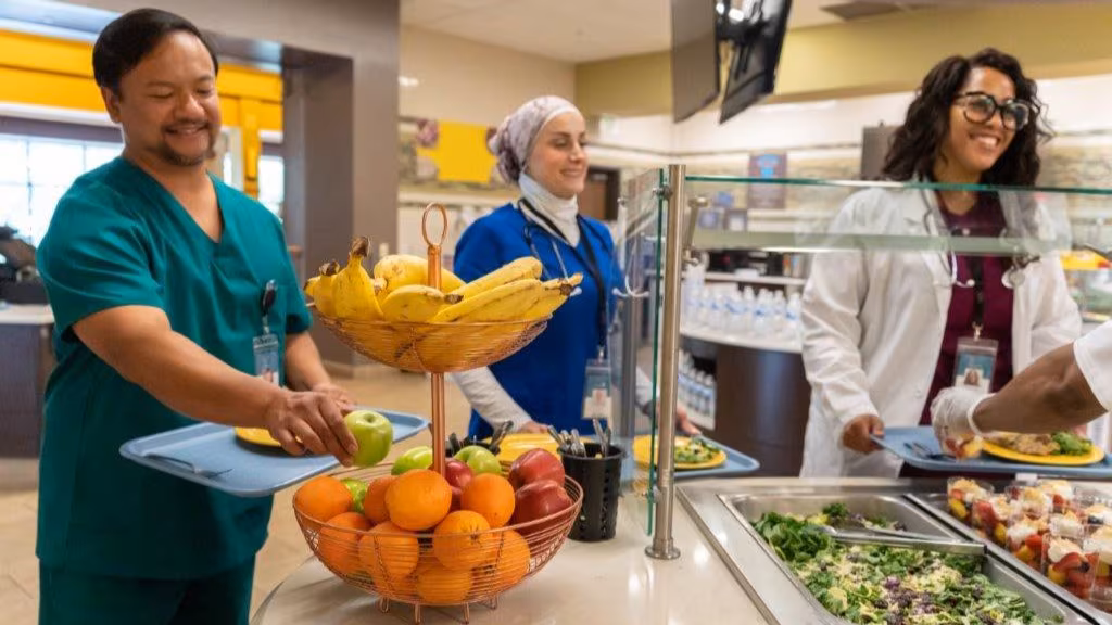 Medical staff choosing healthy options in serving line of hospital cafeteria.