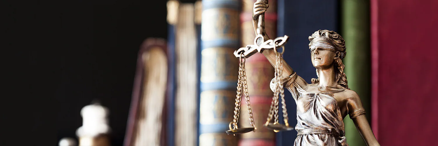 Lady justice statue holding scales with books in the background Lady justice statue holding scales with books in the background
