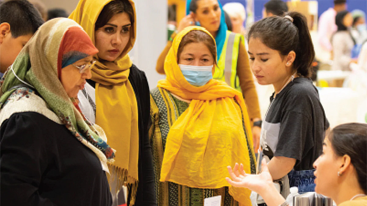 Clarkston Placeholder Women wearing hijabs are assisted by two young women at a gathering.