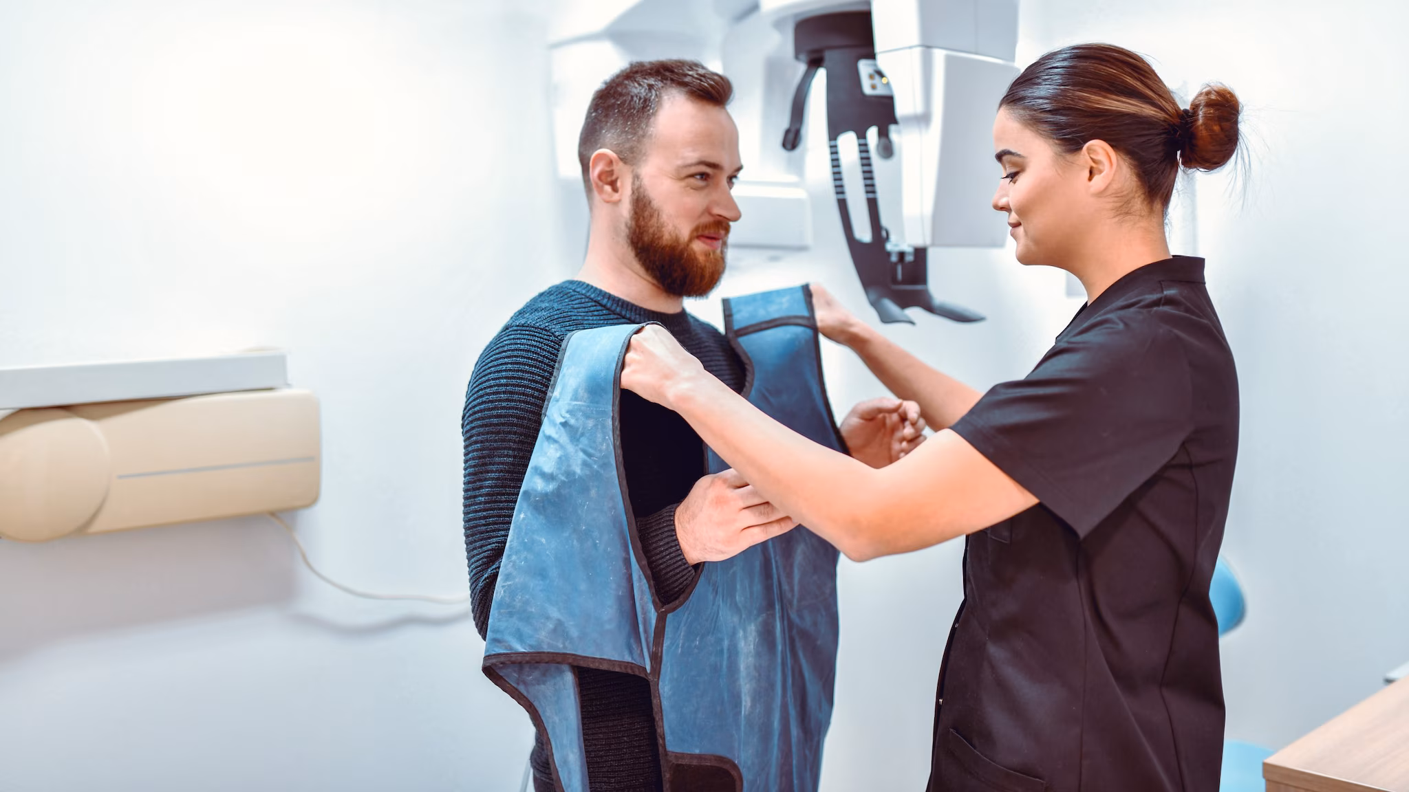 Female dental radiologist preparing male patient for dental computer tomography