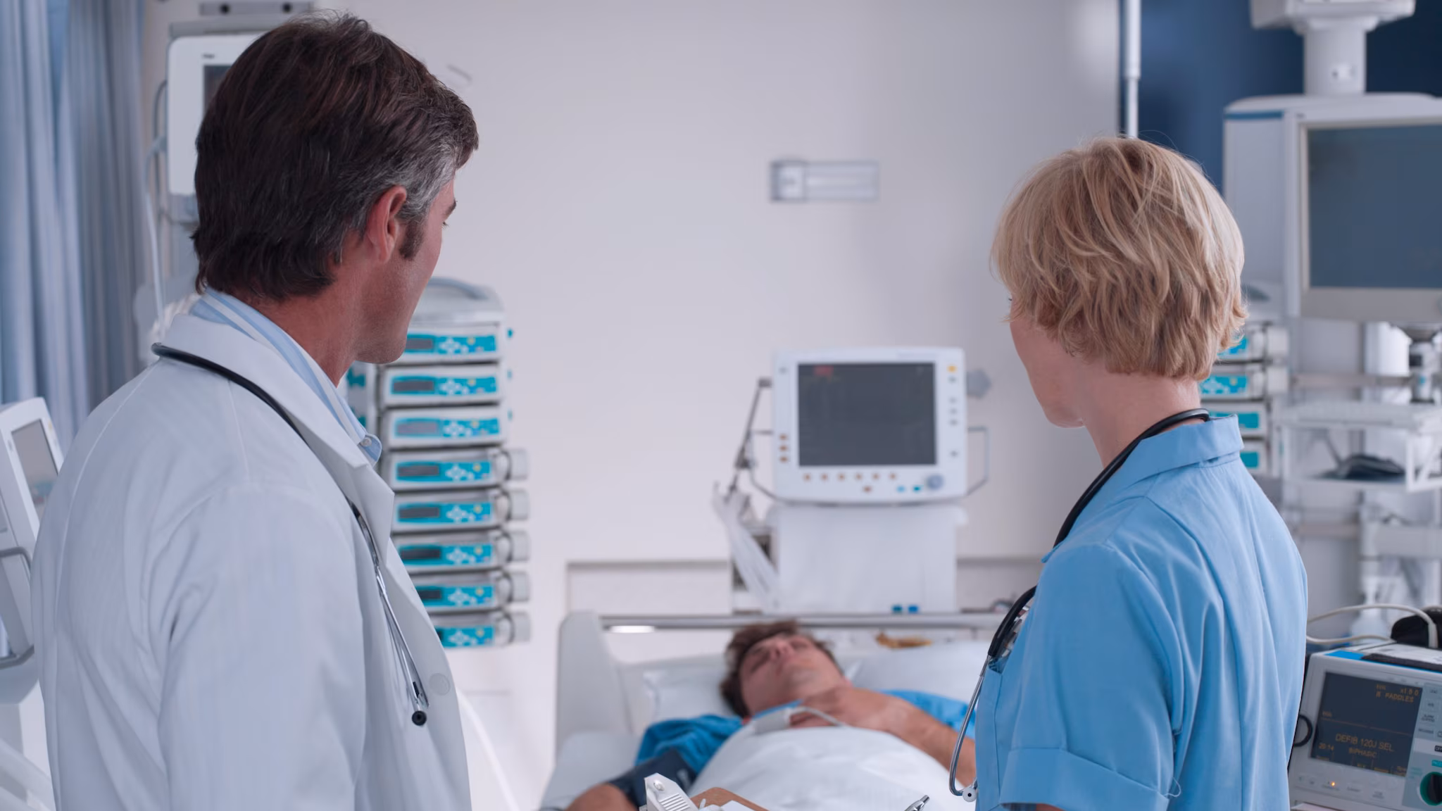 Doctor Nurse Talking ICU Doctor and nurse talking in presence of a patient lying in bed.