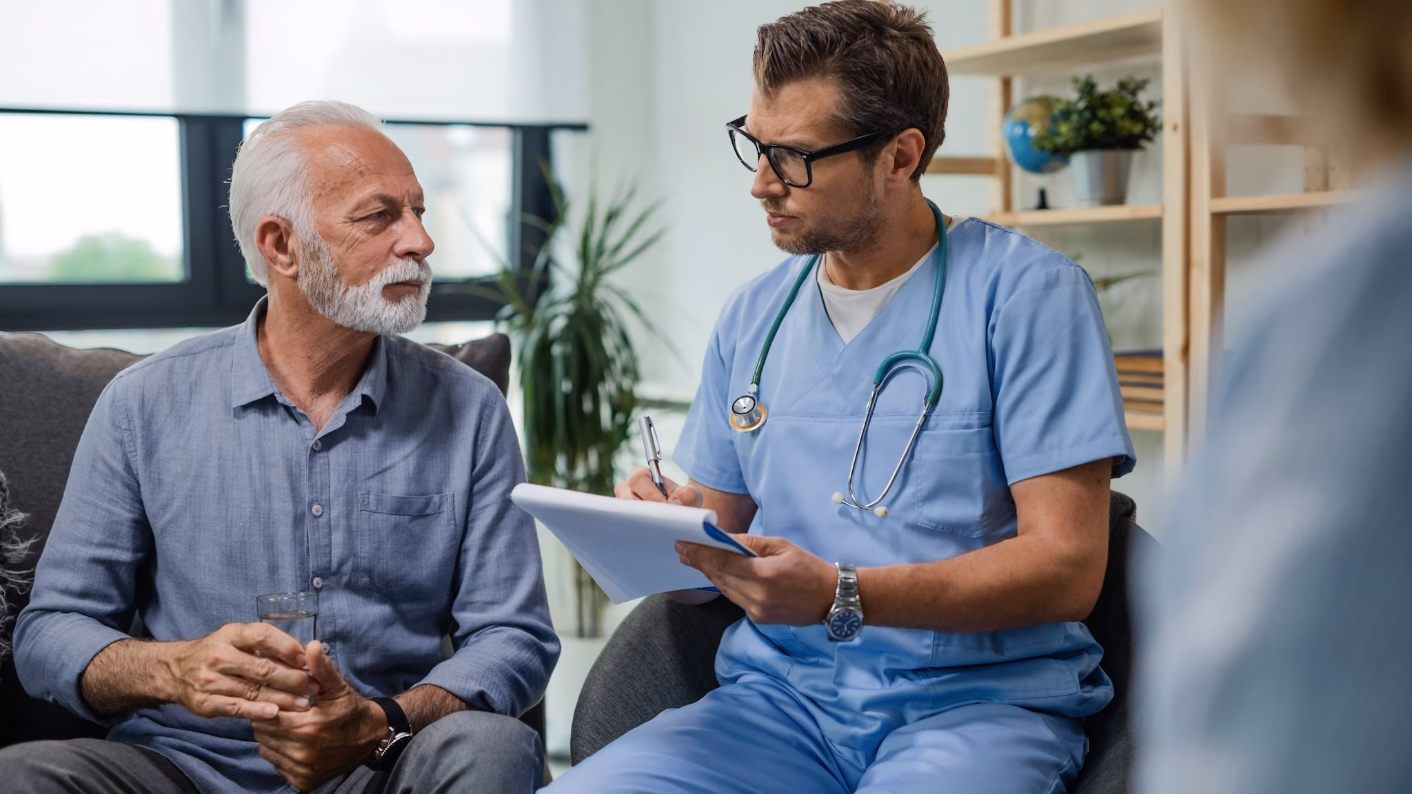 General Practitioner Taking Notes General Practitioner Taking Notes while speaking with an older man