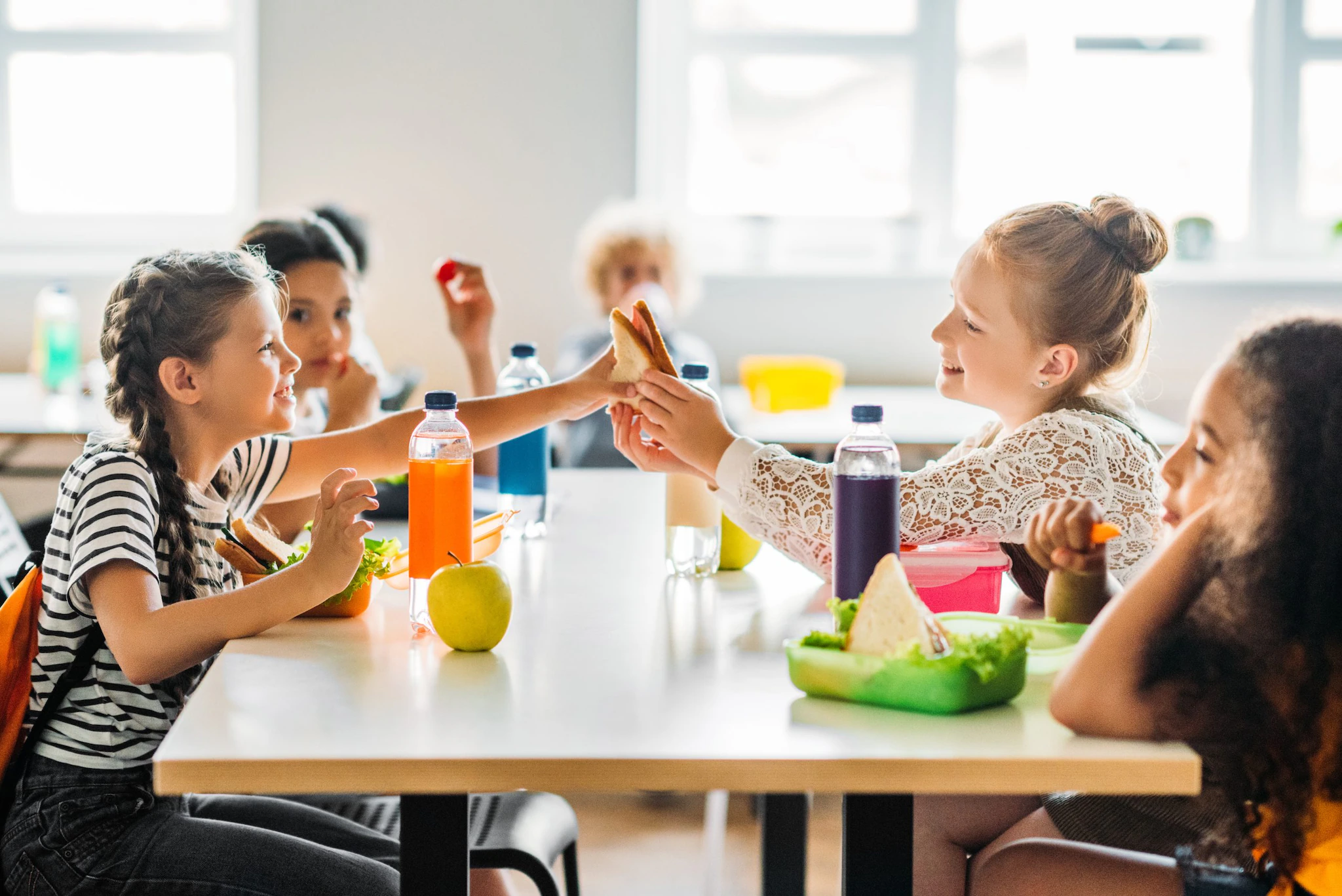 A group of students eating lunch at school. A group of students eating lunch at school.