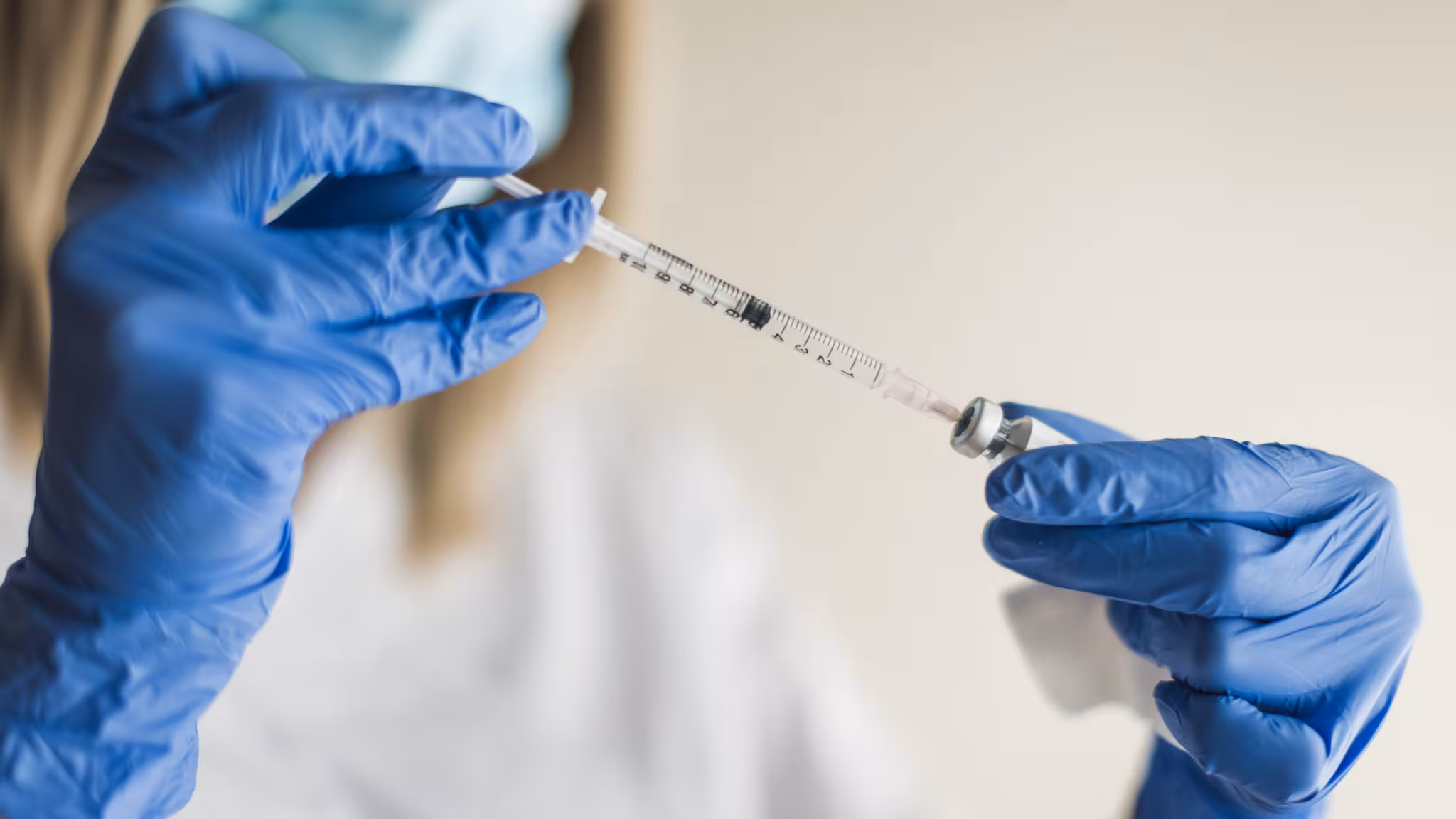 Vaccine vial Healthcare professional inserting a syringe into a vaccine vial