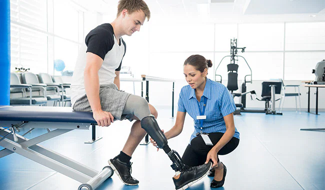 Physical therapist helping a patient put on his prosthetic leg.