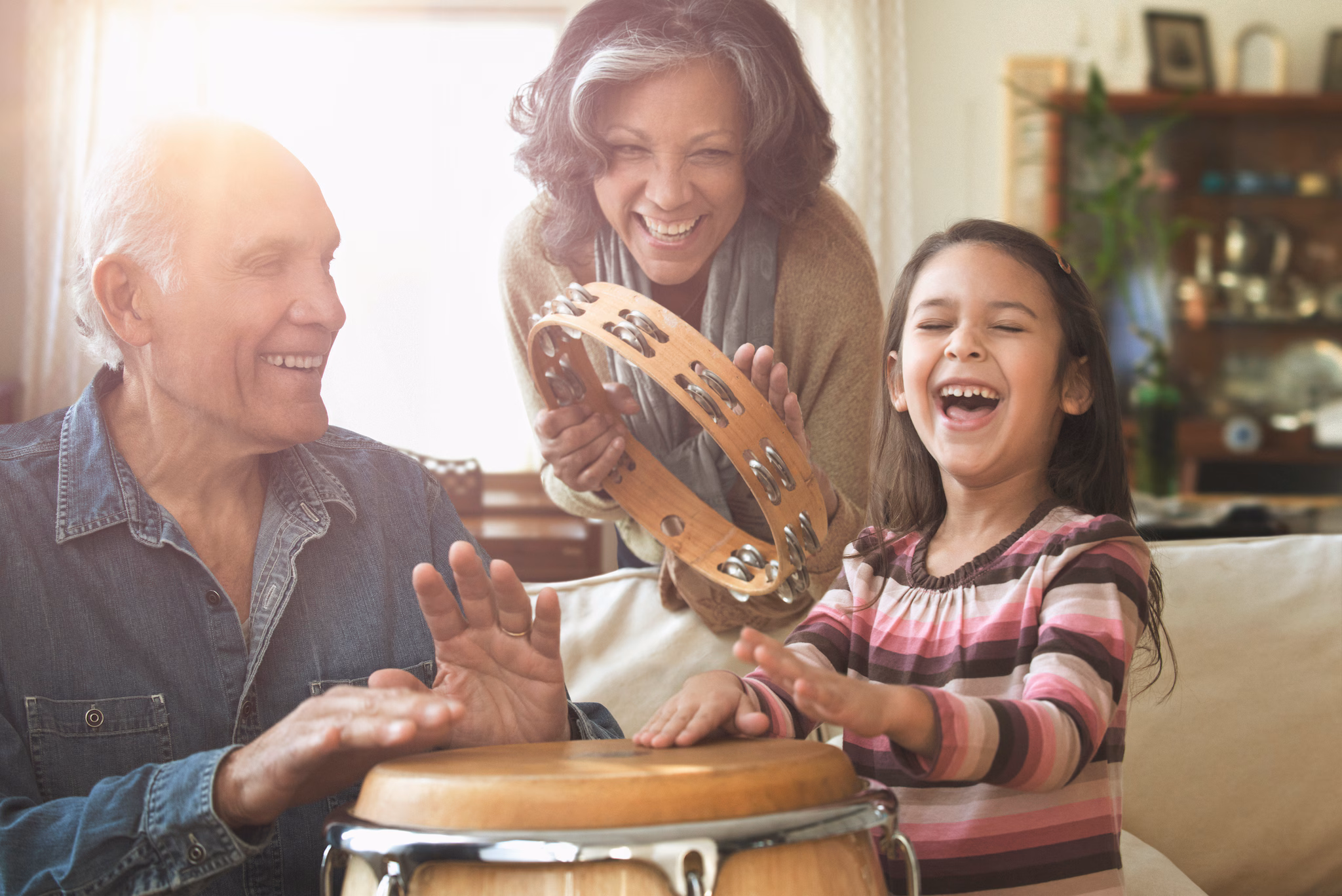 Grandparents and grandchild playing at home Grandparents and grandchild laughing and playing musical instruments together at home.