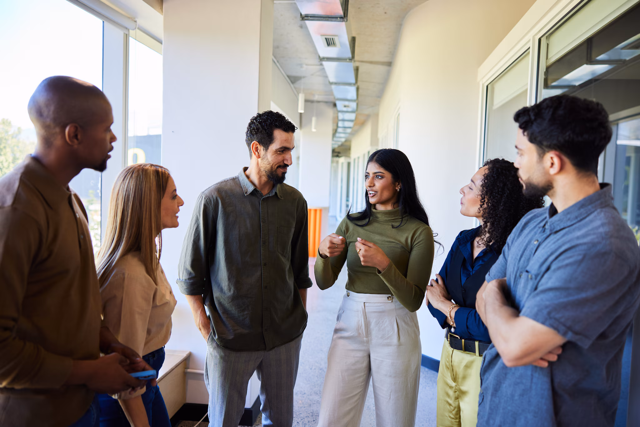 Group of diverse colleagues talking in an office hallway