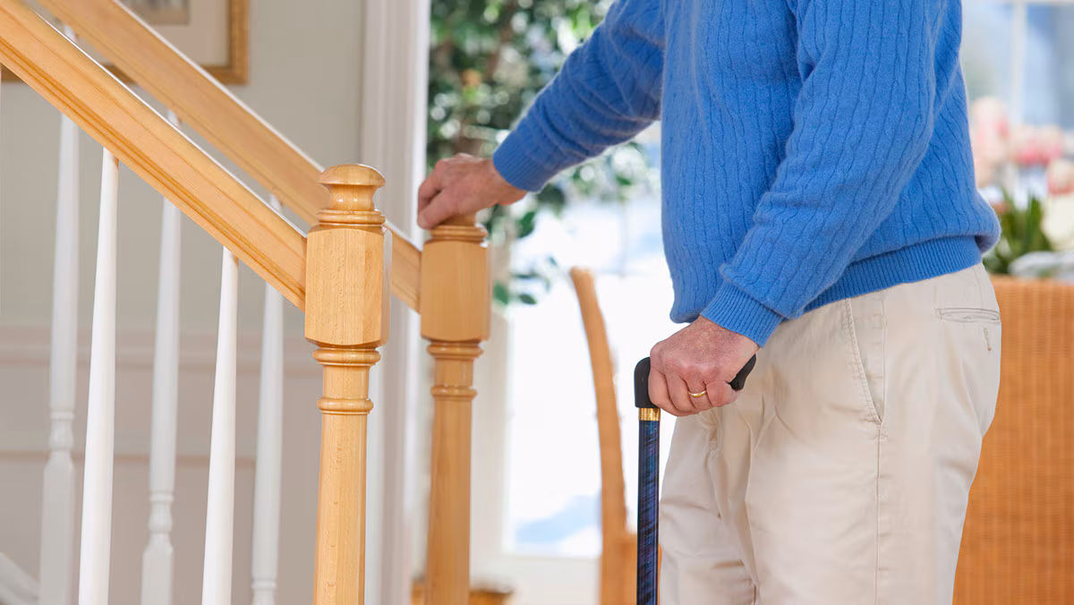 older man with a cane walking up stairs