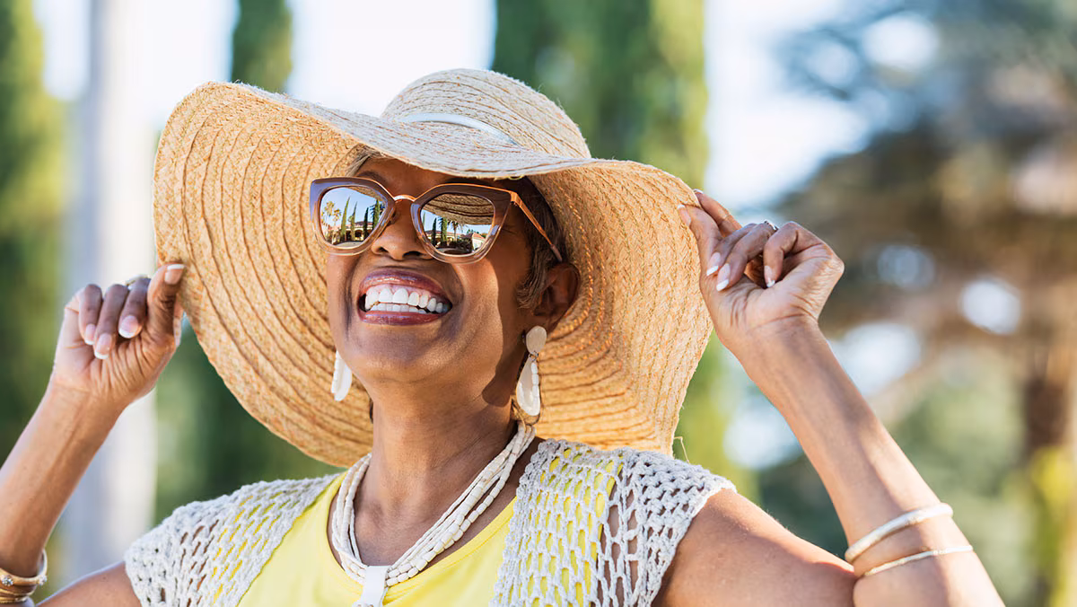 Smiling lady with hat and sunglasses outside