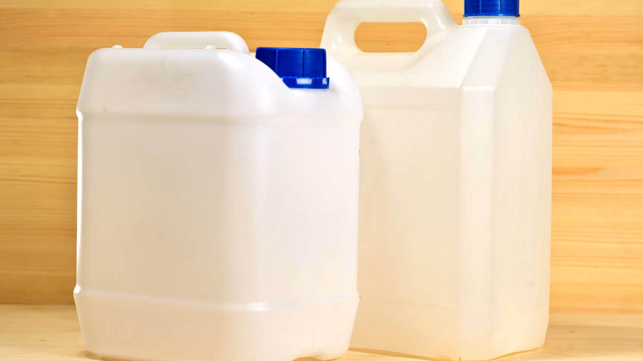 Picture of white plastic gallon containers on the background of wooden wall
