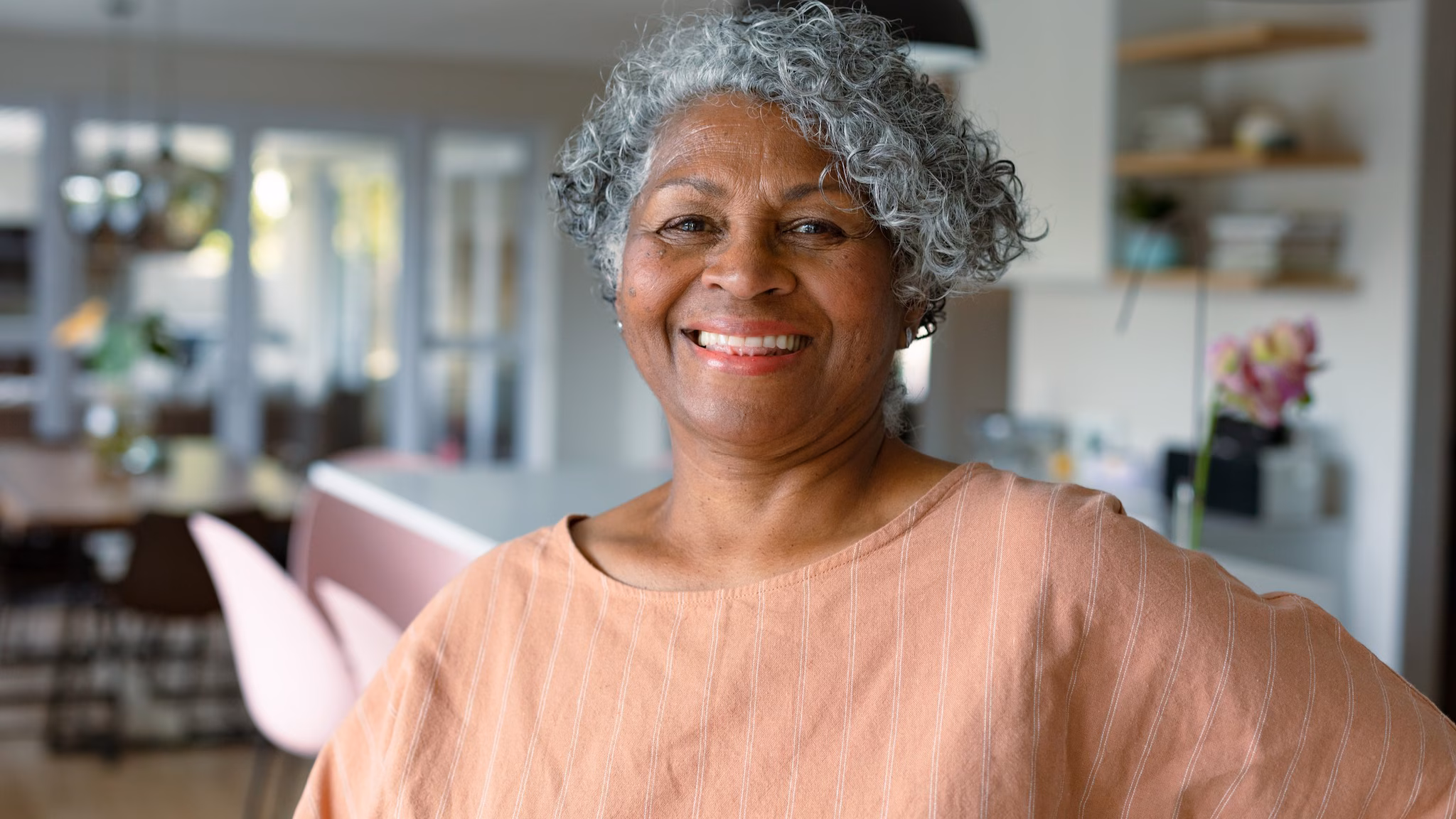An older adult standing in the kitchen indoors.