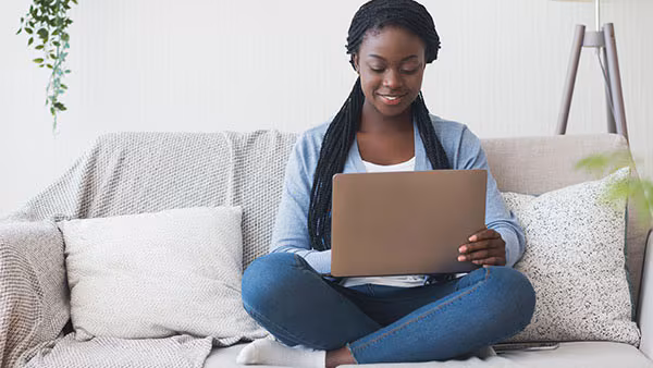 Data request A female educator sitting on the sofa and using laptop.